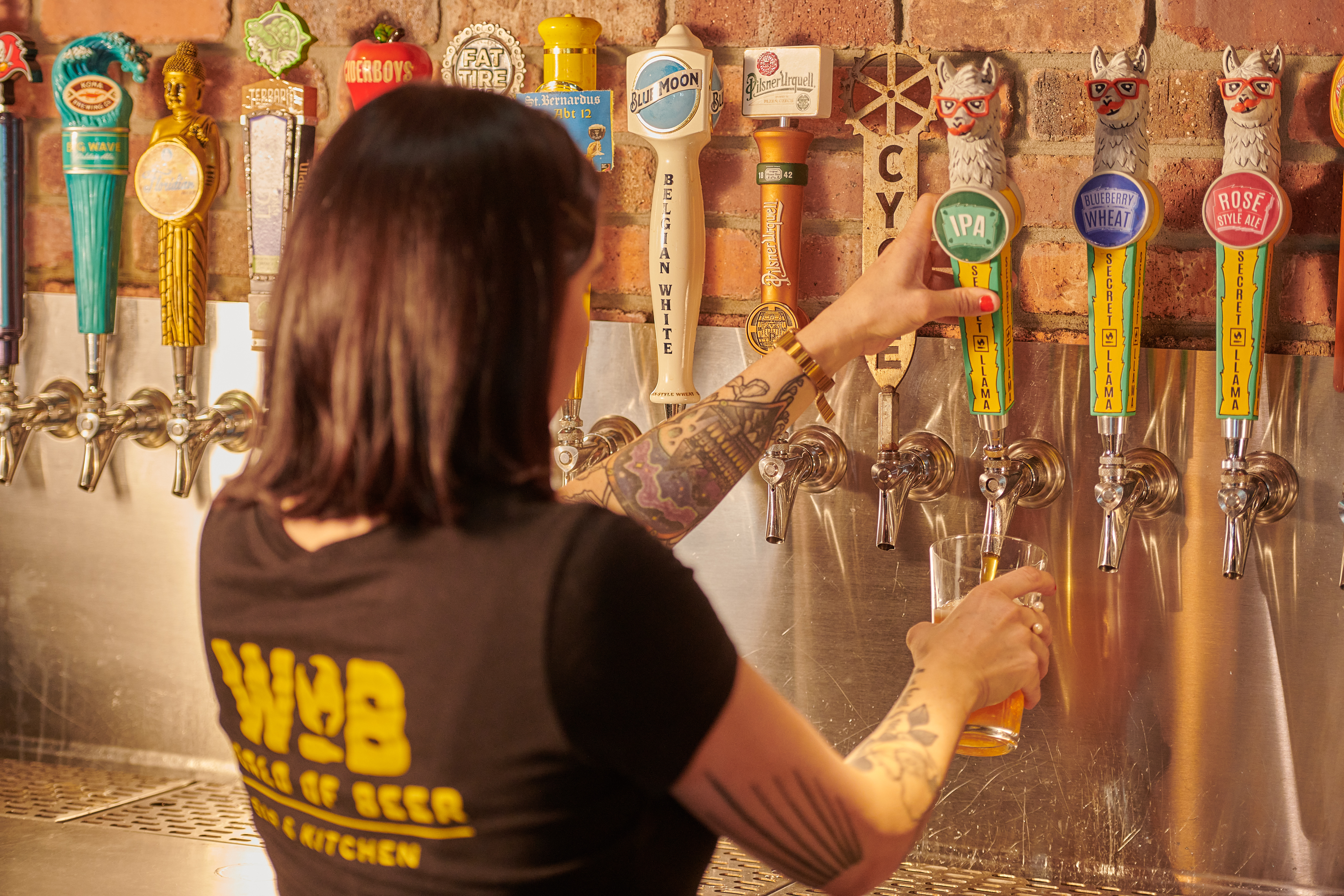 A World of Beer bartender pours Secret Llama IPA from the restaurant beer taps.